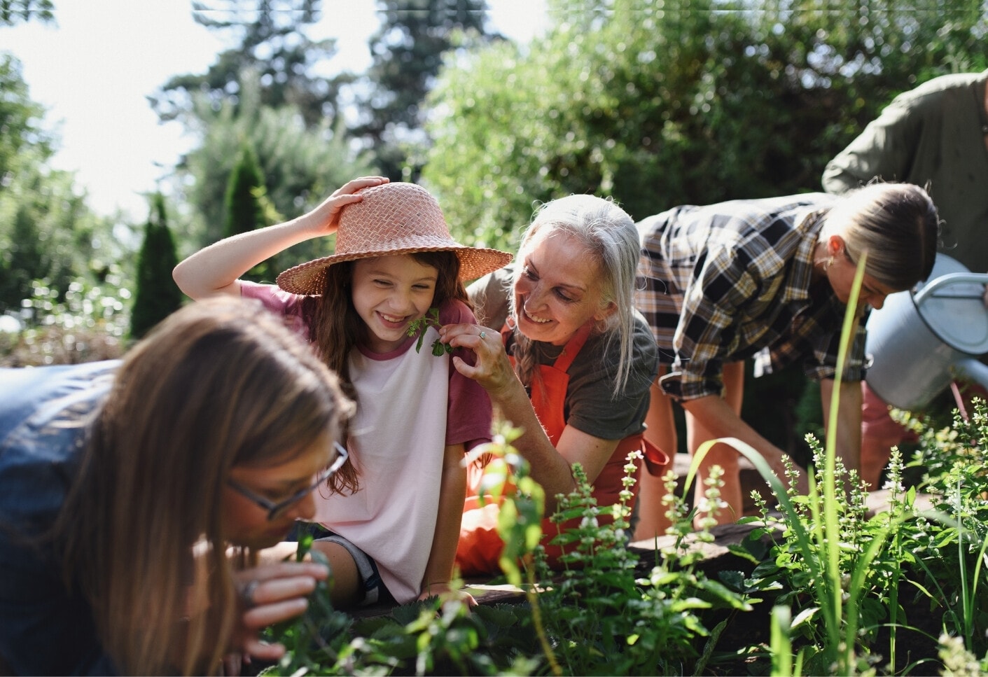 Twee jonge vrouwen, een oudere vrouw en een meisje werken in een moestuin.