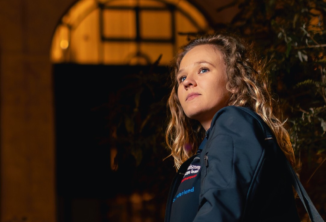 Een portret van een jonge vrouw met blond krullend haar die schuin omhoog kijkt.