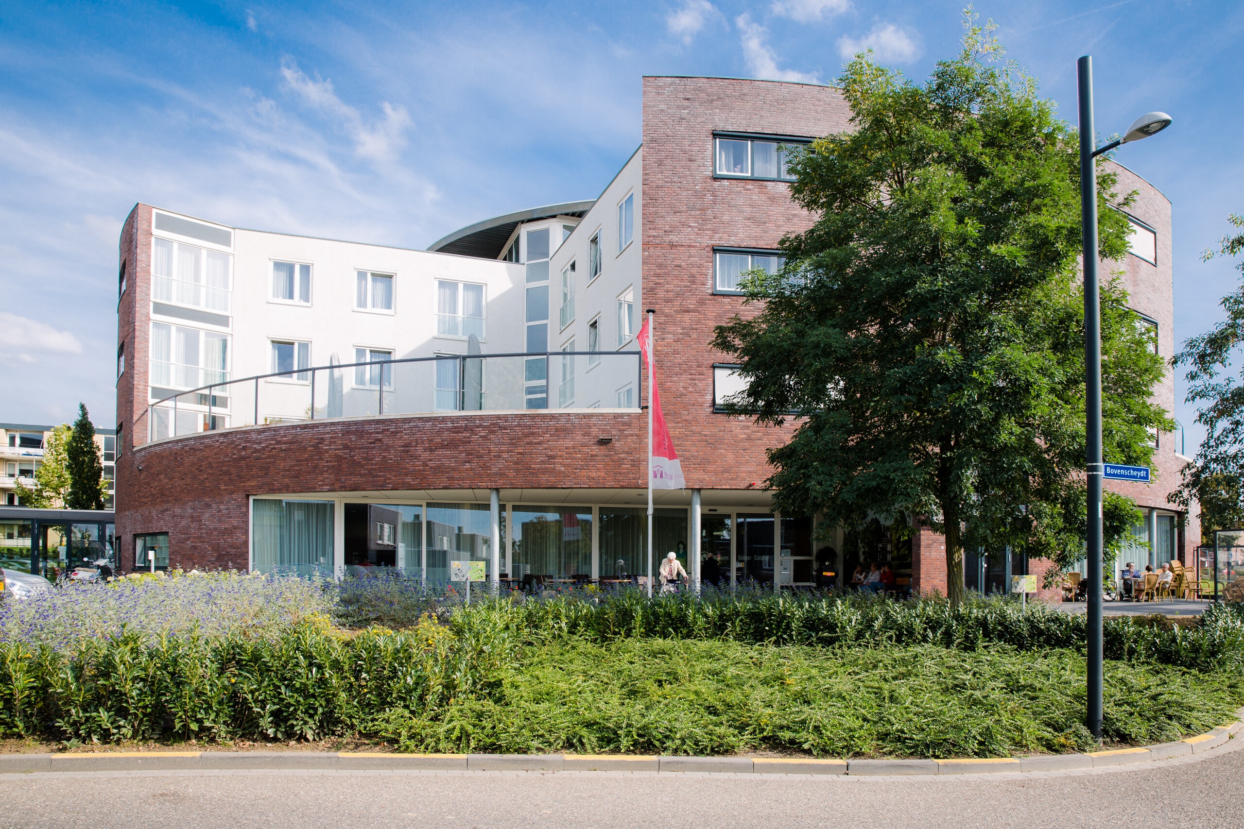 Buitenkant van zorgcomplex Dokter Calshof. Voor het gebouw staat een grote boom.